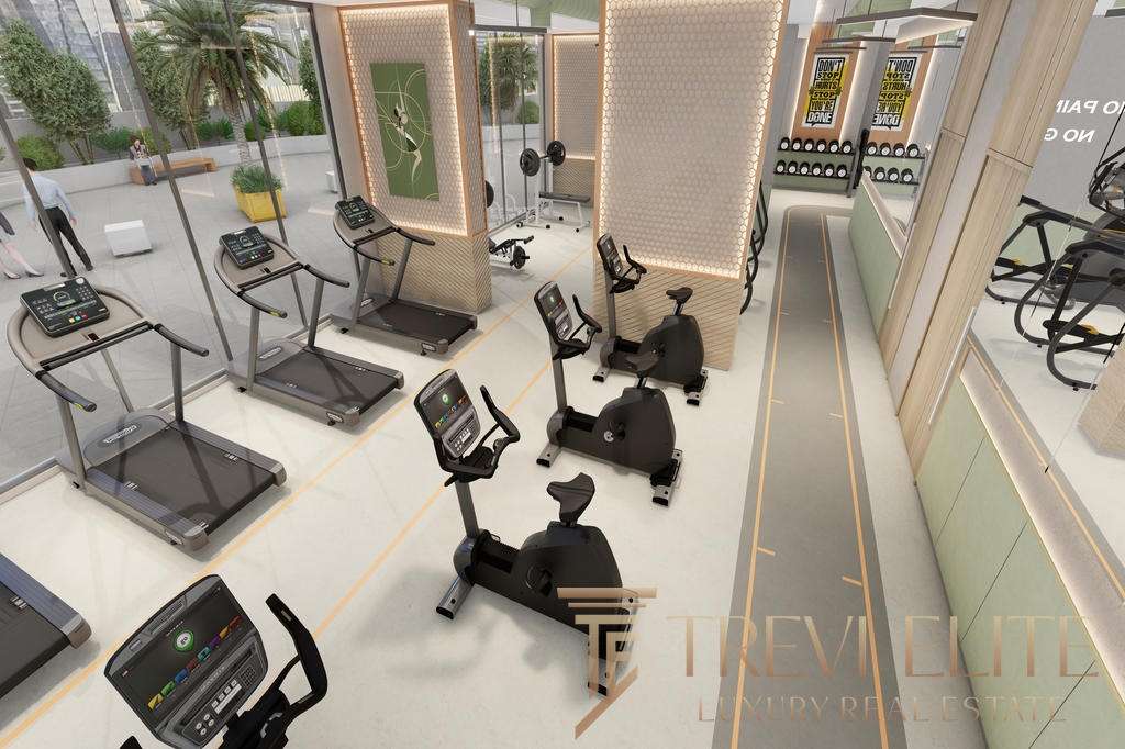 Современный фитнес-зал с кардиотренажерами и тренажерами для интенсивных занятий, благодаря стеклянным стенам в зале открывается вид на город и зеленый двор.
