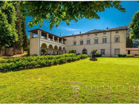 Роскошное итальянское особняк на зеленом лугу, окруженный садами и древними деревьями, под ярким голубым небом, идеальный дом для ценителей элитной недвижимости.