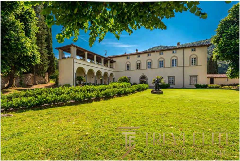 Роскошное итальянское особняк на зеленом лугу, окруженный садами и древними деревьями, под ярким голубым небом, идеальный дом для ценителей элитной недвижимости.