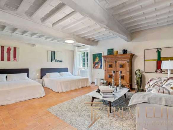 Изображение роскошной гостиной с белыми стенами, деревянной мебелью и уютным интерьером, предлагающее престижную недвижимость в Италии и мире.