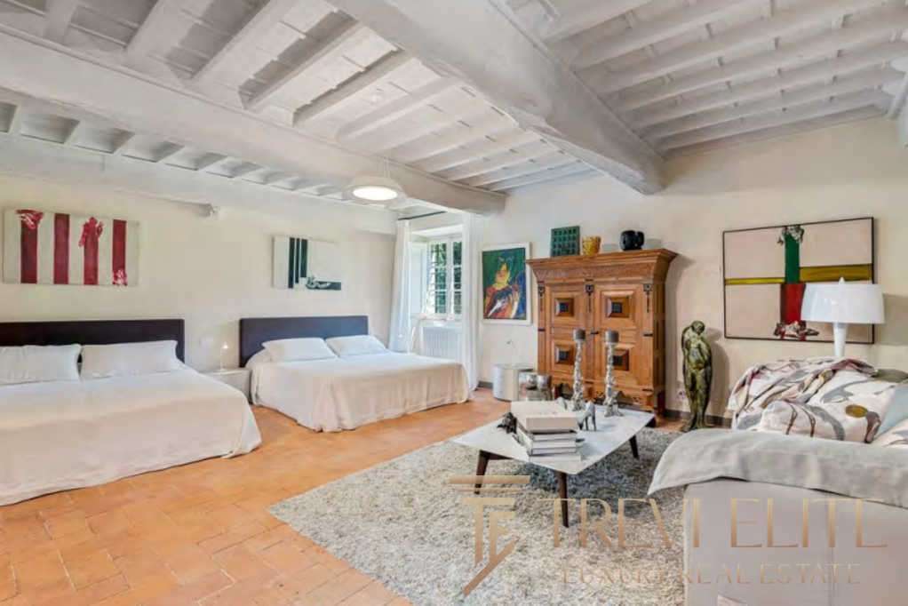 Изображение роскошной гостиной с белыми стенами, деревянной мебелью и уютным интерьером, предлагающее престижную недвижимость в Италии и мире.