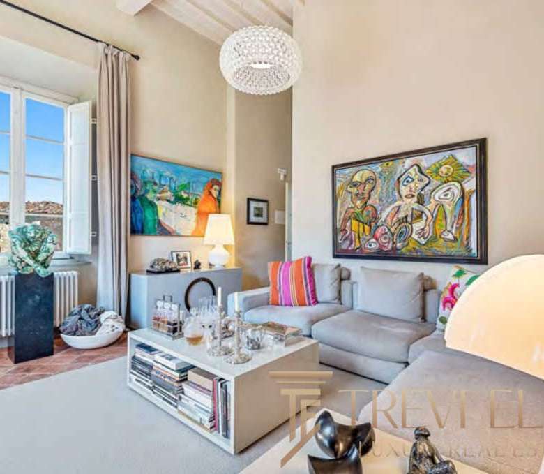 Элегантная гостиная в роскошной квартире с современным интерьером, яркими картинами и уютным освещением, идеально подходит для элитной недвижимости и высокого стиля жизни.