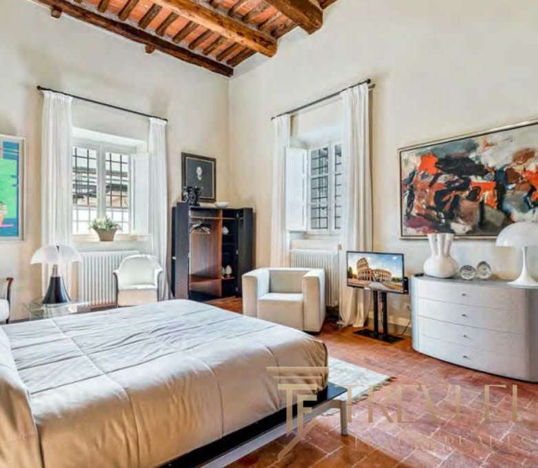 Элегантная спальня в роскошной итальянской недвижимости, светлый интерьер с живописными произведениями искусства и уютной атмосферой, идеальное жилье для ценителей эксклюзивных объектов.