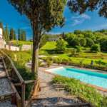 Уединенный роскошный дом с бассейном на фоне живописных зеленых холмов и деревьев, окруженный природой и итальянским пейзажем, идеальный для элитного отдыха и инвестиций.