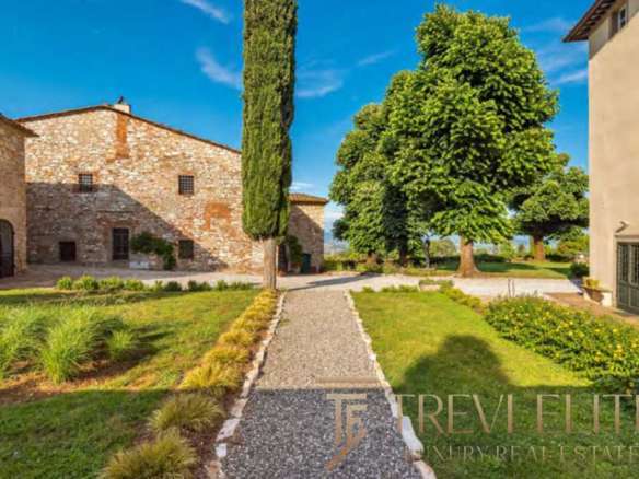 Уютная деревенская территория с историческими кирпичными зданиями, живописной зеленью и ярким голубым небом, идеально отражающая атмосферу элитной недвижимости Треви Элит.