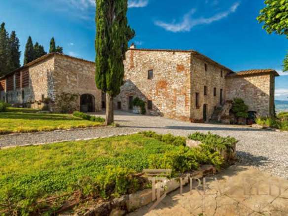 Средневековая каменная усадьба в живописной итальянской деревушке, окруженная зеленью и грациозными деревьями, под ярким небом и солнечным светом.