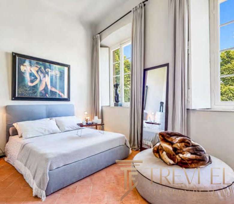 Современная спальня в стиле роскошного итальянского дома с большими окнами, светлыми стенами и уютной атмосферой.