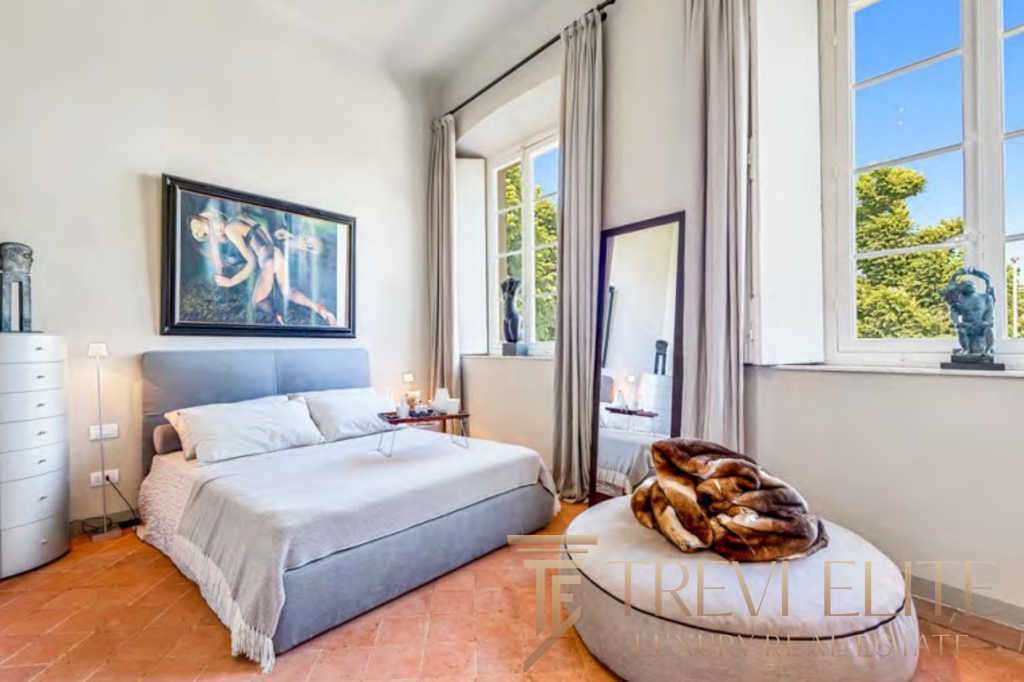 Современная спальня в стиле роскошного итальянского дома с большими окнами, светлыми стенами и уютной атмосферой.