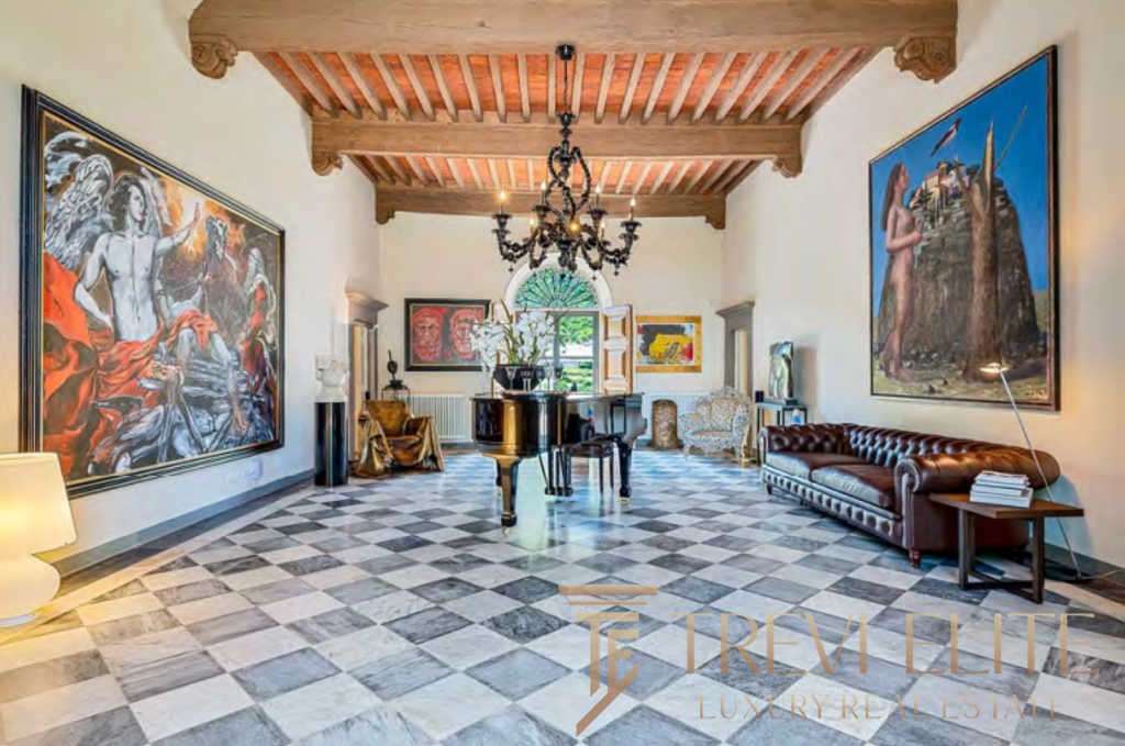 Роскошная зал с антикварным пианином, художественными картинами и уютной мебелью в стиле итальянской аутентичности, под деревянным потолком и элегантной люстрой.