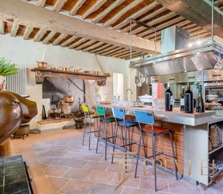 Роскошная кухня в стиле итальянского рустика с современными элементами, деревянным потолком и камином, идеальным для элитных резиденций и премиальных клиентов.