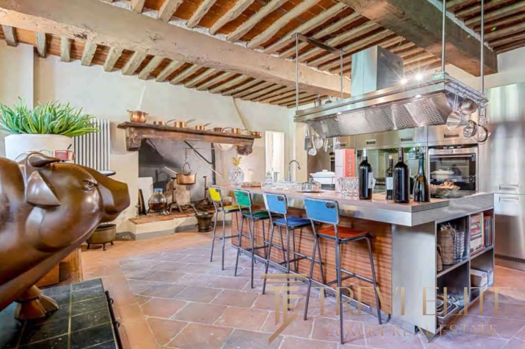 Роскошная кухня в стиле итальянского рустика с современными элементами, деревянным потолком и камином, идеальным для элитных резиденций и премиальных клиентов.