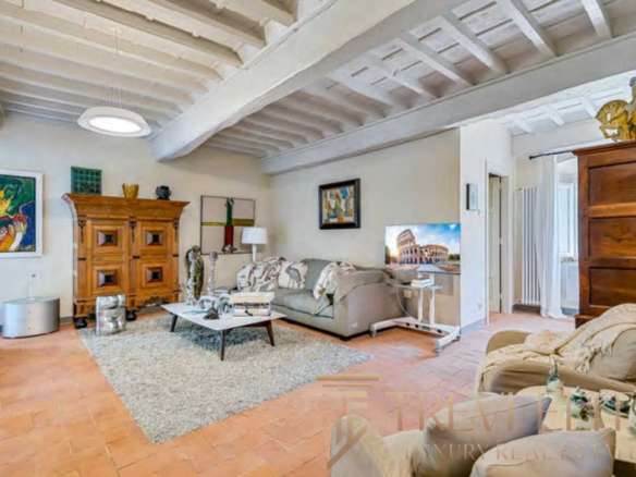 Элегантная гостиная с деревянной мебелью и уютной атмосферой в роскошном итальянском доме. Светлые стены и дизайнерские элементы создают гармоничное пространство для отдыха.