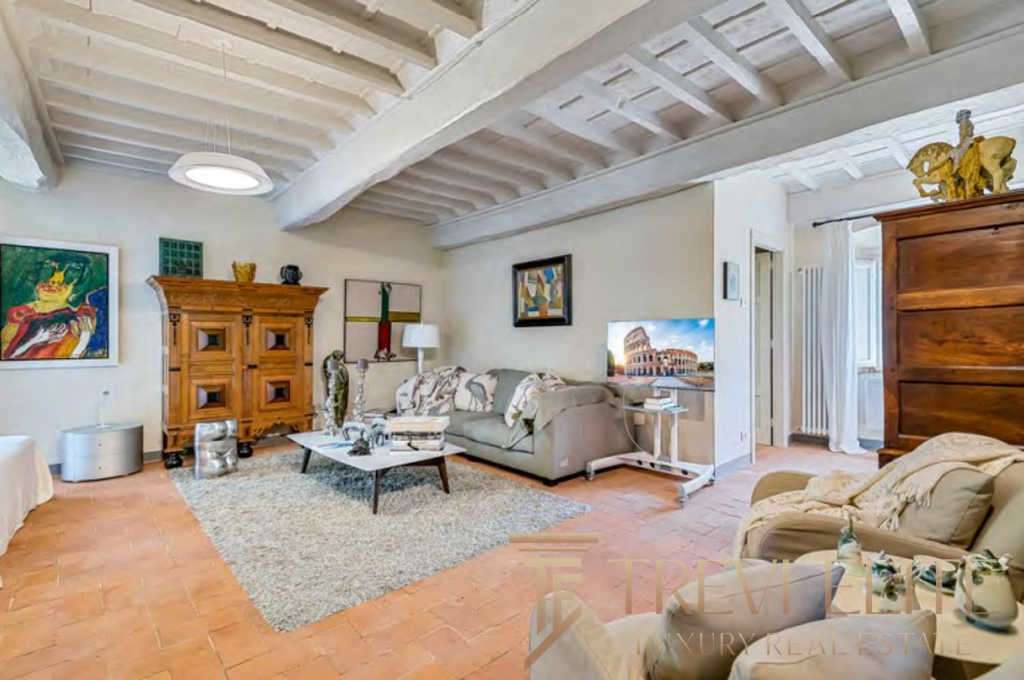 Элегантная гостиная с деревянной мебелью и уютной атмосферой в роскошном итальянском доме. Светлые стены и дизайнерские элементы создают гармоничное пространство для отдыха.