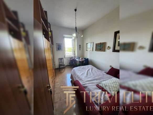 Уютная спальня в стильной квартире с яркими картинами на стенах и большой кроватью, просторной комнатой и светлым окном, создающим атмосферу комфорта и роскоши.