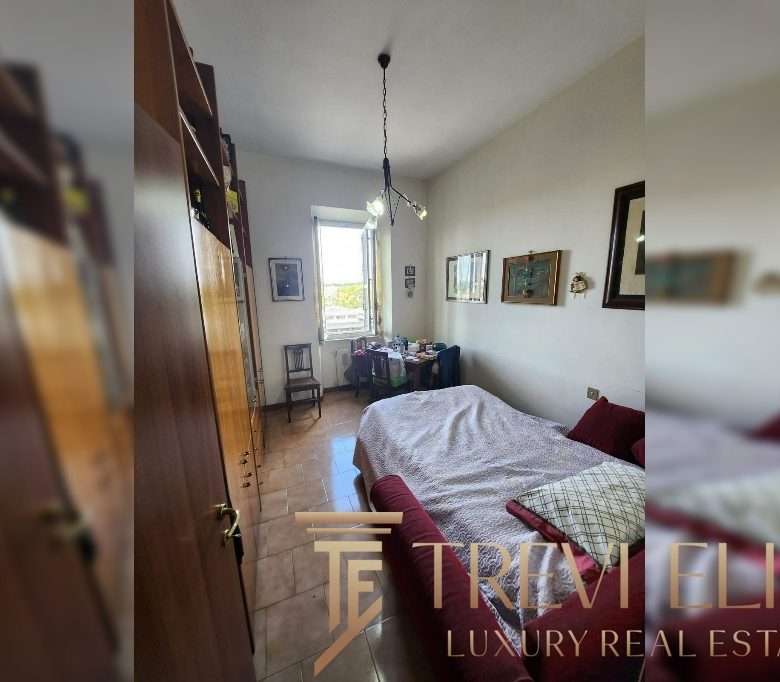 Уютная спальня в стильной квартире с яркими картинами на стенах и большой кроватью, просторной комнатой и светлым окном, создающим атмосферу комфорта и роскоши.