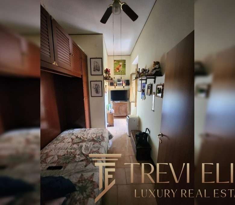 Уютная комната с деревянной мебелью и телевизором, оформление в домашних стилях, фотографии и картины на стенах, светлый интерьер, подходящий для комфортного проживания.