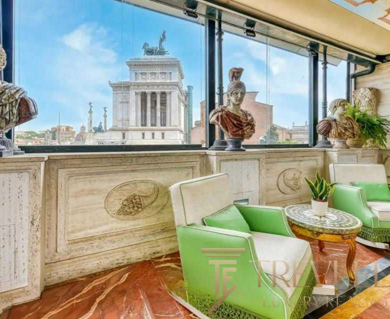 Бюсты древнегреческих и римских фигур, витрина с панорамным видом на Римские руины, уютная зона отдыха с мягкой мебелью и зелеными растениями в эксклюзивном агентстве недвижимости Треви Элит.