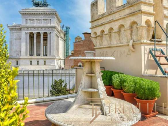 Элитный балкон с видом на архитектурные достопримечательности Рима, украшенный зеленью и уютной мраморной мебелью, идеальное место для отдыха и наслаждения городской атмосферой.