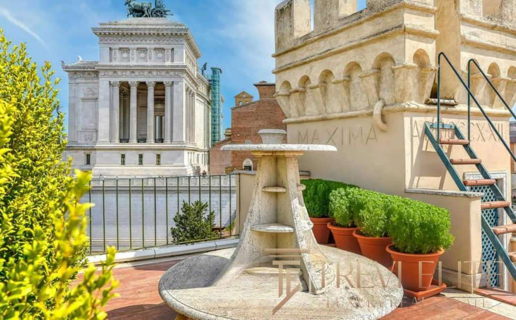 Элитный балкон с видом на архитектурные достопримечательности Рима, украшенный зеленью и уютной мраморной мебелью, идеальное место для отдыха и наслаждения городской атмосферой.