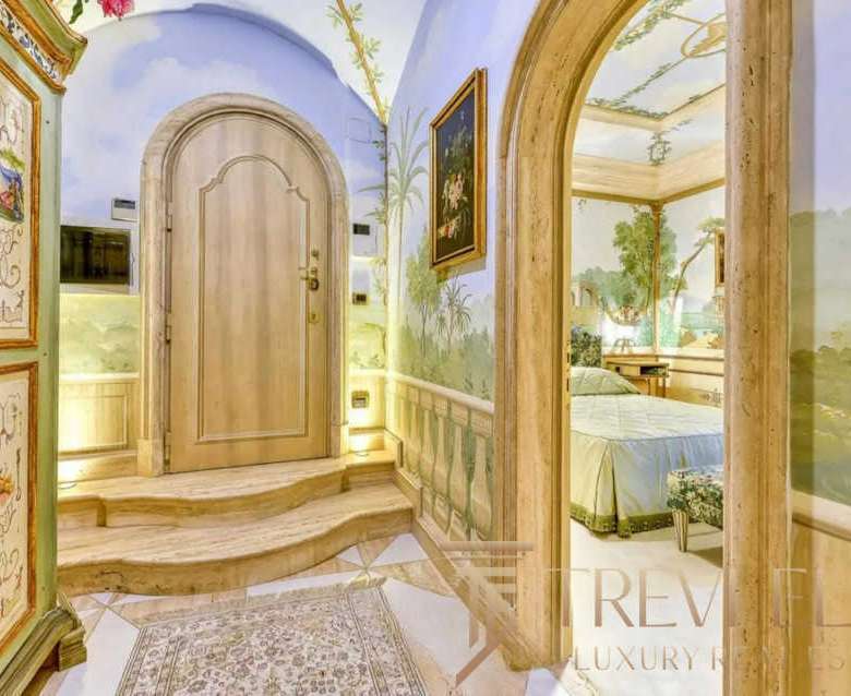 Элегантный вход с расписными стенами и декоративными элементами, ведущий в роскошную гостиную с классическим стилем и живописными пейзажами на стенах. haute couture interior design.