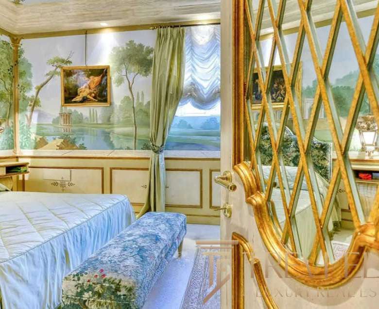 Роскошная спальня в элитной итальянской недвижимости с изысканным интерьером, лепниной и художественной росписью на стенах, создающая атмосферу уюта и статуса.