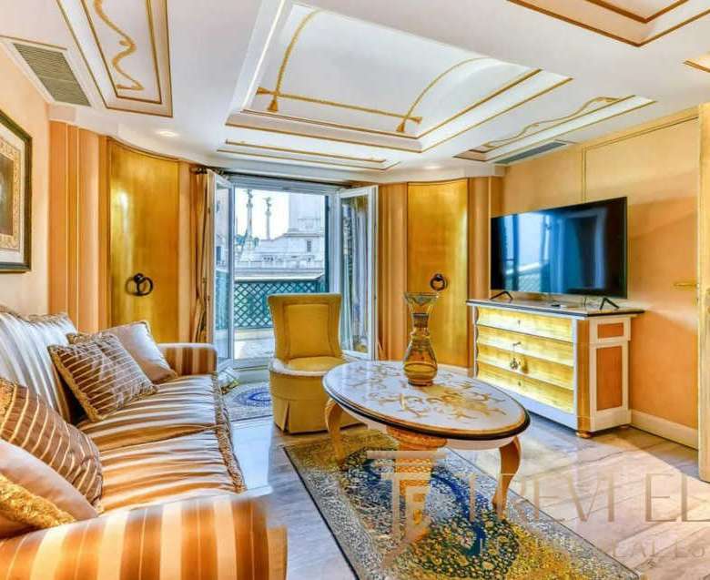 Элитная гостиная с уютным диваном, классическими картинами и балконным доступом, создающая ощущение роскоши и комфорта в эксклюзивных итальянских апартаментах.