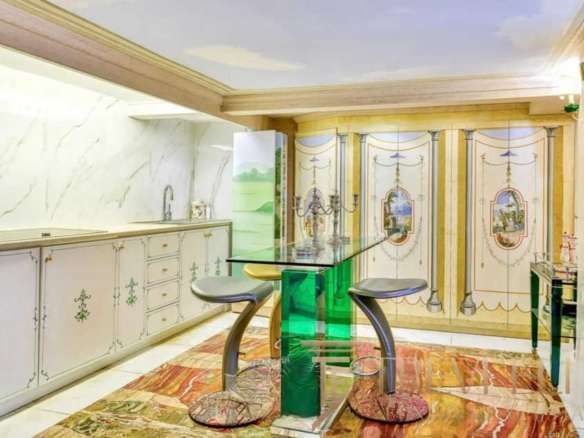 Элегантная кухня в классическом стиле с лепниной и декоративными панелями, светлым интерьером и уютной атмосферой, идеально подходящая для роскошной недвижимости высокого класса.