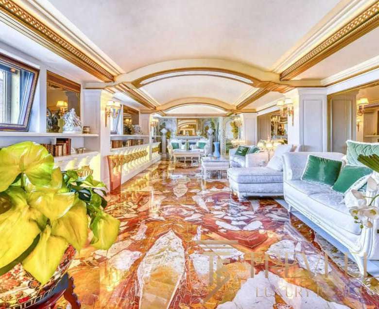 Роскошный интерьер салона с яркими декоративными элементами и высоким потолком в стиле классика. Великолепное освещение, уютный дизайн и элегантная мебель подчеркивают престиж агентства недвижимости Треви Элит.