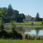 Объемный пейзаж на берегу озера с домом и окружающей природой в солнечный день, идеально подходит для элитной недвижимости за границей.