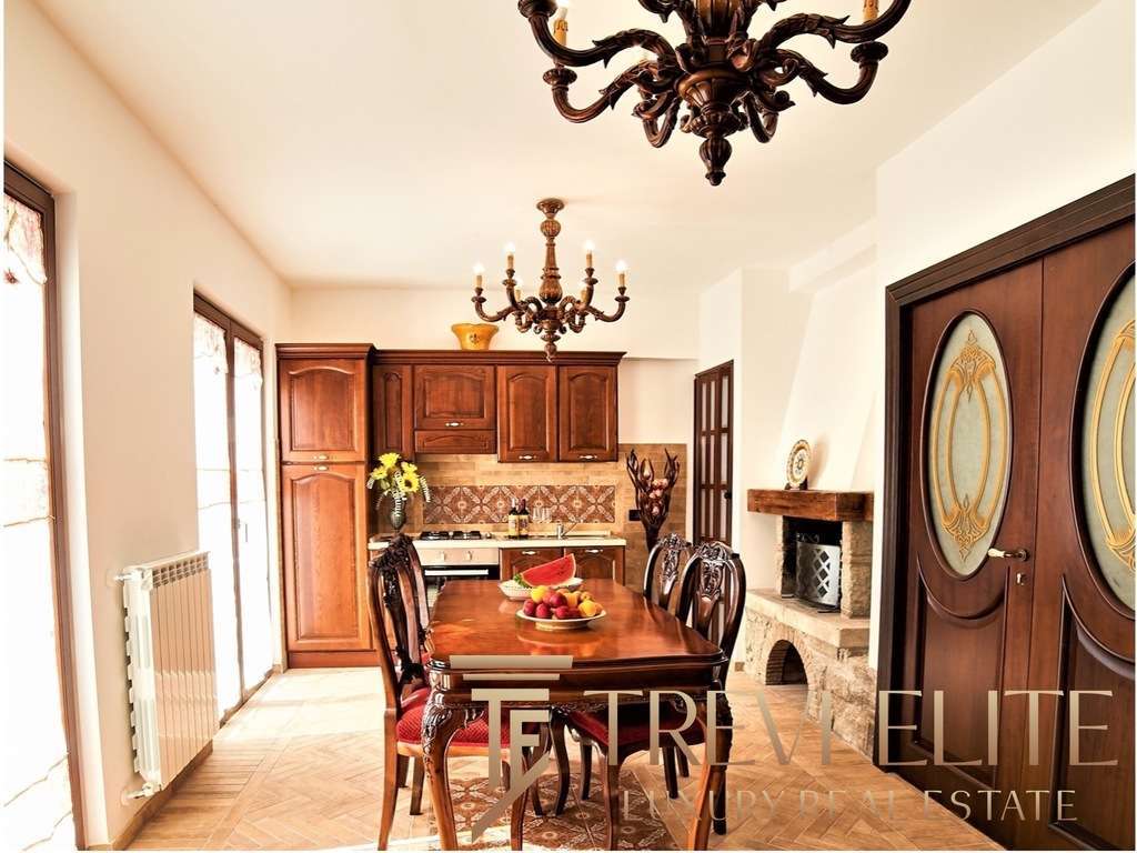 утрасолнечный интерьер с классической мебелью и камином в уютной кухне-столовой, деревянные шкафы и декоративные элементы, теплое освещение, стильное оформление для элитных недвижимости в Италии и мире.