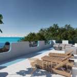 Роскошная терраса у моря с видом на океан, украшенная стильной мебелью и шезлонгами, окружена зеленью, идеально подходит для отдыха и наслаждения красивыми панорамами.