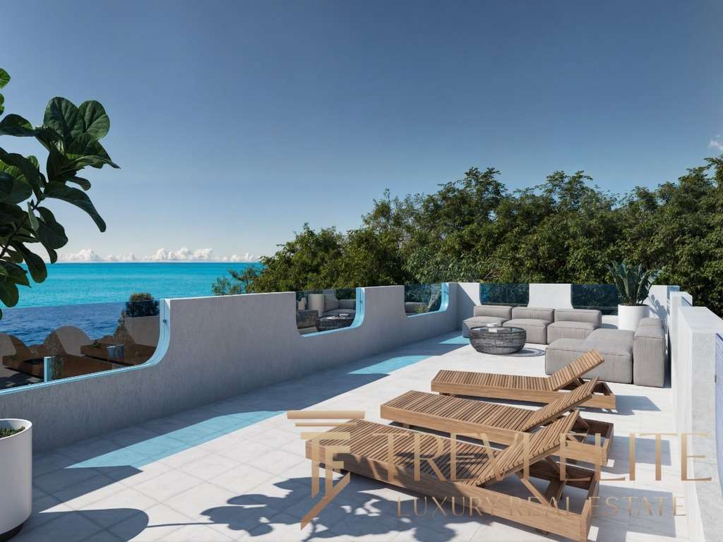 Роскошная терраса у моря с видом на океан, украшенная стильной мебелью и шезлонгами, окружена зеленью, идеально подходит для отдыха и наслаждения красивыми панорамами.