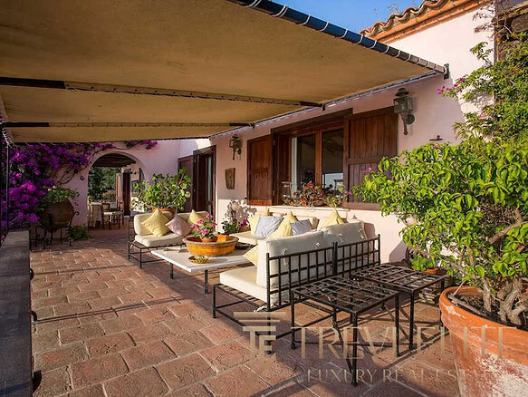 Элегантная терраса с уютной зоной отдыха на открытом воздухе, окруженная живописной зеленью и яркими цветами, идеально подходит для роскошного отдыха и развлечений.