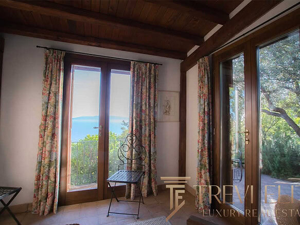 Уютный интерьер с большими деревянными окнами и живописным видом на природу и море, что создает атмосферу спокойствия и уединения. Идеальное решение для любителей природы и роскошной жизни.