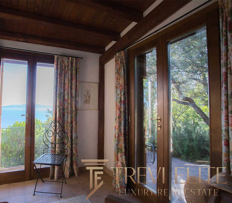 Уютный интерьер с большими деревянными окнами и живописным видом на природу и море, что создает атмосферу спокойствия и уединения. Идеальное решение для любителей природы и роскошной жизни.