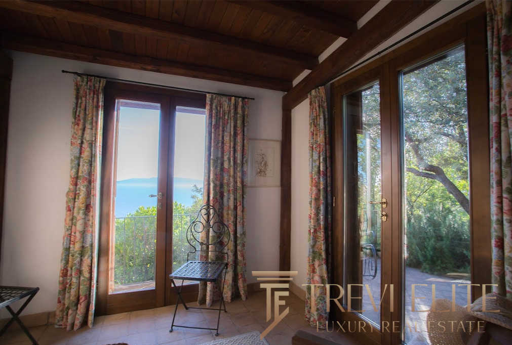 Уютный интерьер с большими деревянными окнами и живописным видом на природу и море, что создает атмосферу спокойствия и уединения. Идеальное решение для любителей природы и роскошной жизни.