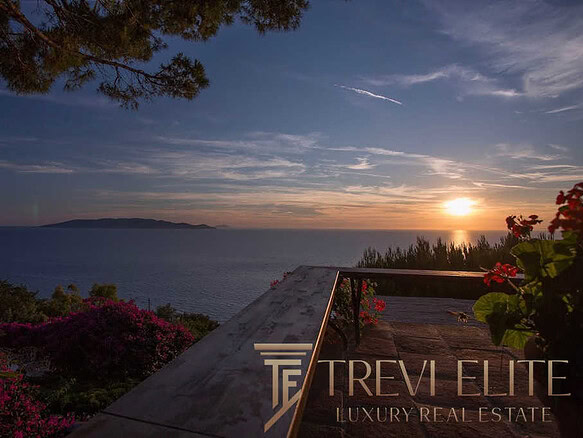 Восхитительный закат над морем с видом на остров, окружённый зеленью и яркими цветами, передающий атмосферу роскоши и эксклюзивности элитной недвижимости.