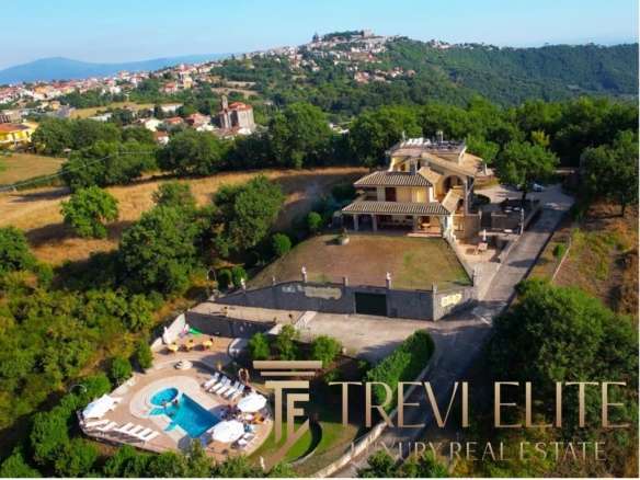 Роскошный загородный дом с бассейном и ухоженным садом на зеленом холме в живописном районе, предлагающий уединение и комфорт для ценителей элитной недвижимости.