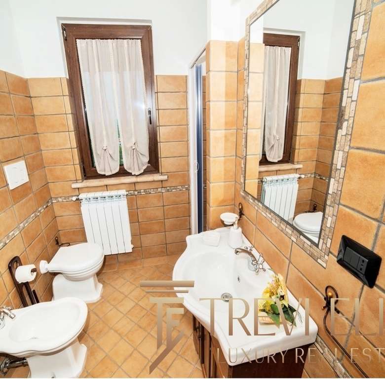 Современная ванная комната с теплой отделкой из керамической плитки, стильным зеркалом и классической сантехникой в элитной недвижимости от Треви Элит.