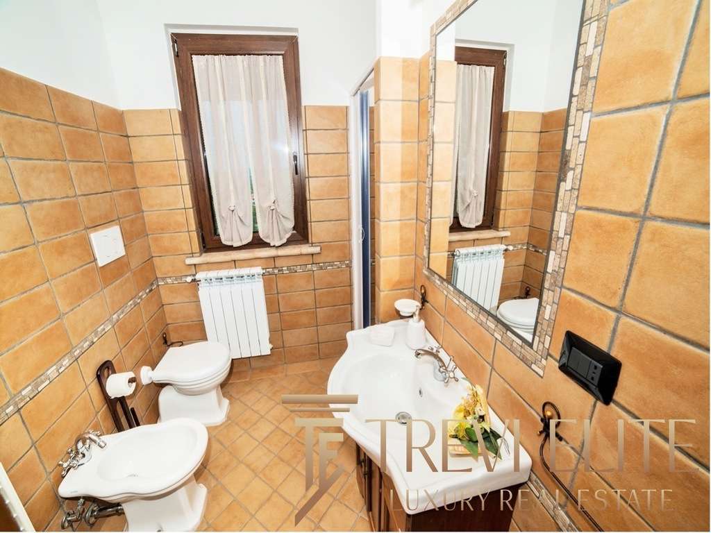 Современная ванная комната с теплой отделкой из керамической плитки, стильным зеркалом и классической сантехникой в элитной недвижимости от Треви Элит.