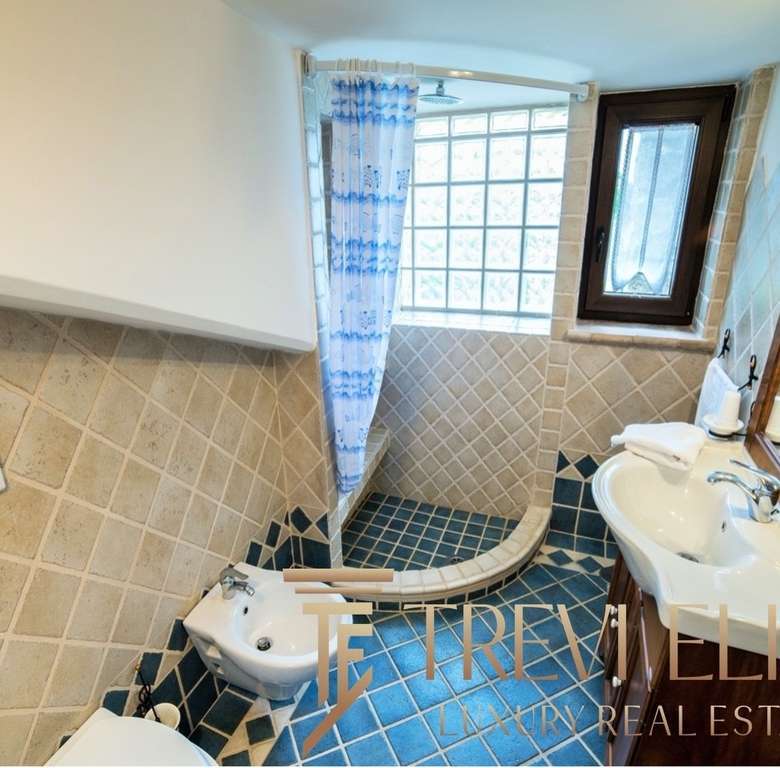 Современная роскошная ванная комната с душевой кабиной, умывальником и большими окнами, создающими светлую и уютную атмосферу в элитной недвижимости Треви Элит.