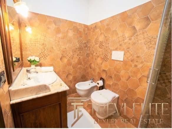 Изображение современного дизайнерского санузла с терраццо плиткой на стенах, деревянной мебелью, утварью и стильным освещением. Идеальное сочетание роскоши и комфорта в элитной недвижимости.