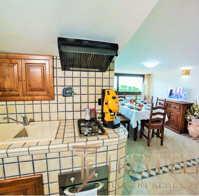 Декоративная кухня с деревянными шкафами и плиткой в стиле кантри, соединяющаяся с обеденной зоной и выходом на террасу с видом на природу. Отличное решение для уютных домашних трапез.