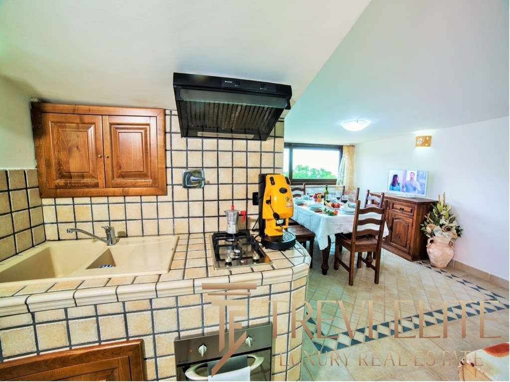 Декоративная кухня с деревянными шкафами и плиткой в стиле кантри, соединяющаяся с обеденной зоной и выходом на террасу с видом на природу. Отличное решение для уютных домашних трапез.