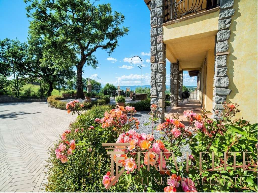 Уютный сад у виллы с яркими розовыми цветами и натуральной каменной отделкой, создающий атмосферу роскоши и спокойствия.