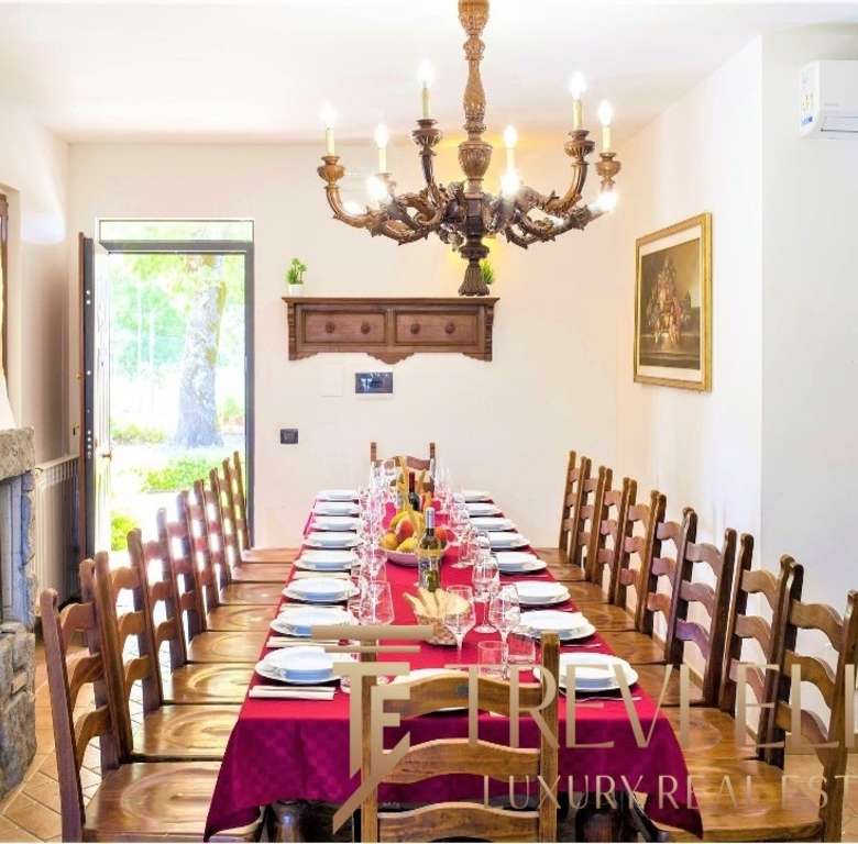 Уютная обеденная зона с длинным столом, сервированным для торжественного приема, классическая мебель и романтичное освещение создают атмосферу роскоши и уюта.