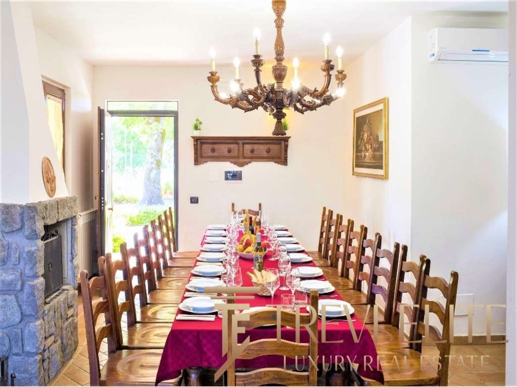 Уютная обеденная зона с длинным столом, сервированным для торжественного приема, классическая мебель и романтичное освещение создают атмосферу роскоши и уюта.