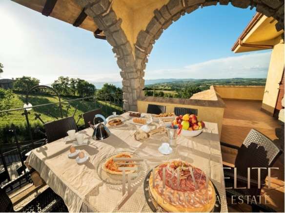 Роскошный веранда с видом на итальянские холмы, уютный обеденный стол, свежие продукты, яркое солнце, идеальное место для отдыха и наслаждения природой.