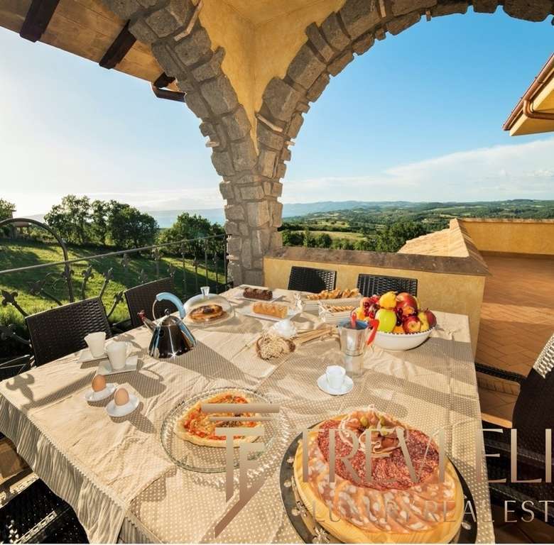 Роскошный веранда с видом на итальянские холмы, уютный обеденный стол, свежие продукты, яркое солнце, идеальное место для отдыха и наслаждения природой.