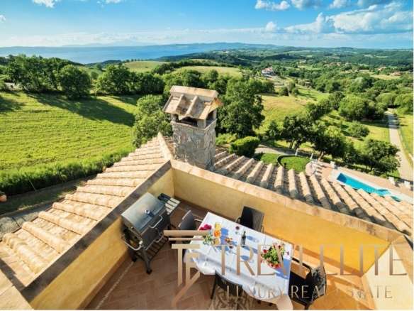 Планировка с террасы с видом на зеленую сельскую местность и море у горизонта, роскошный дом на холме с террасой и камином, популярное место для отдыха и развлечений.